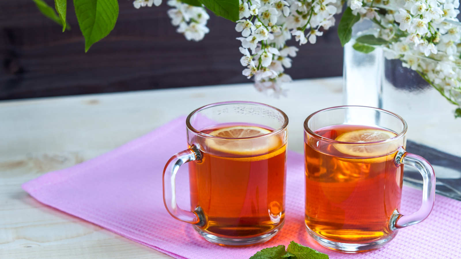 Две чашки чая с лимоном на столе с цветами 