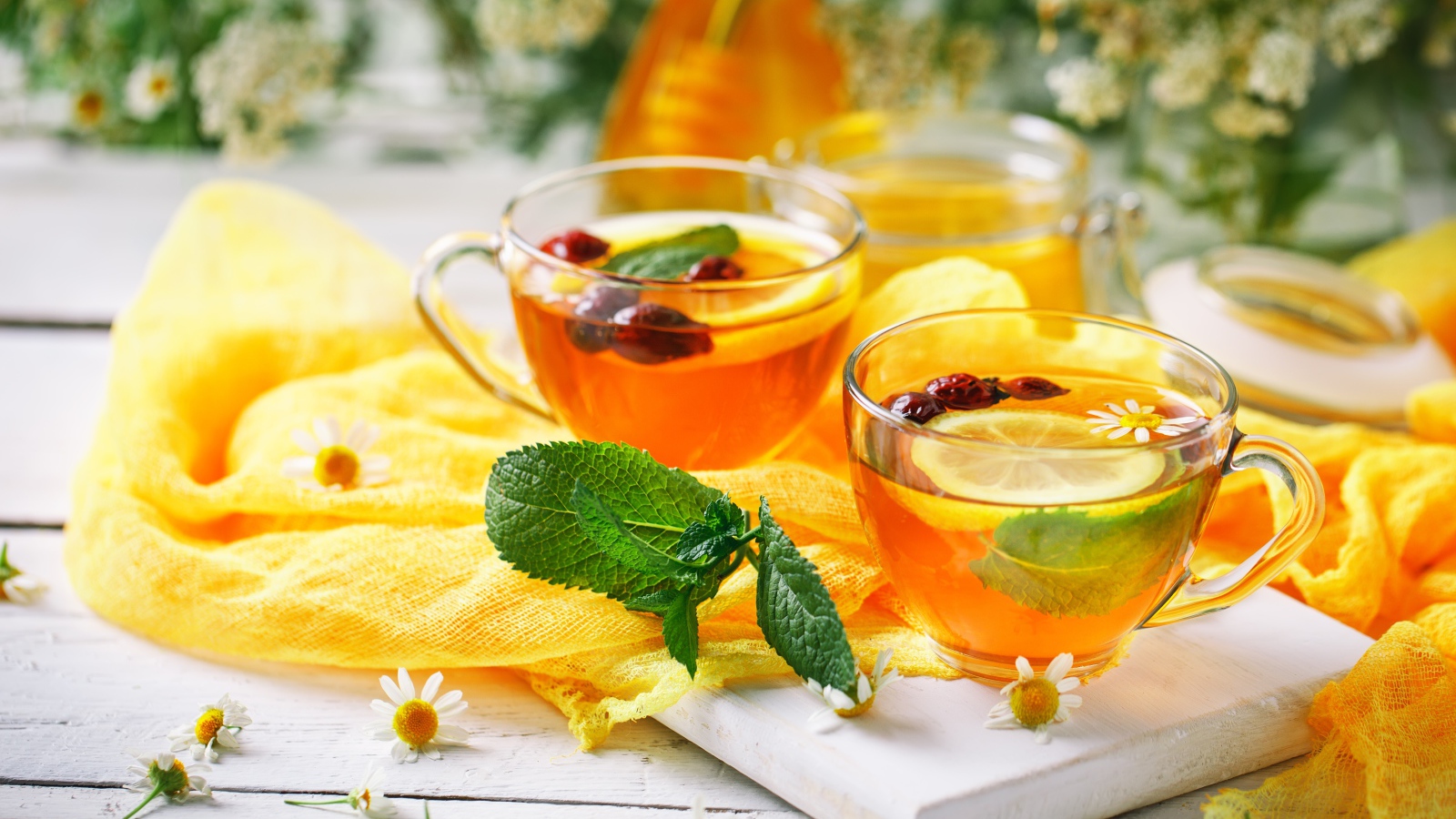 Две стеклянные чашки чая с лимоном, мятой и шиповником