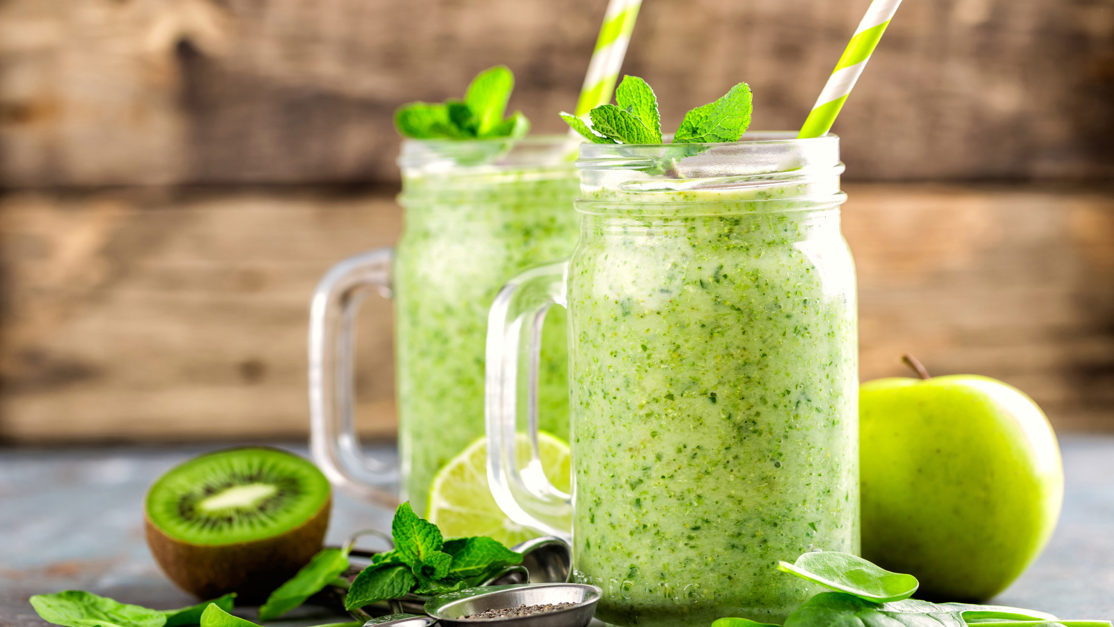Два зеленых смузи на столе с киви, мятой и зеленым яблоком