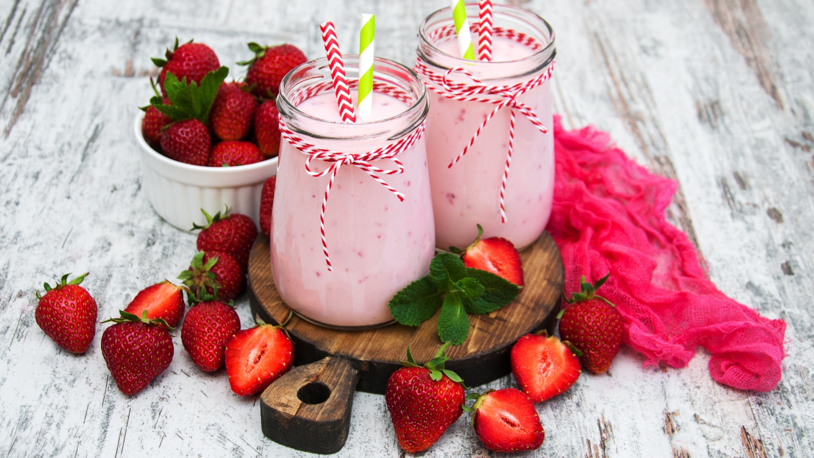 Две банки смузи стоят на доске на столе с клубникой