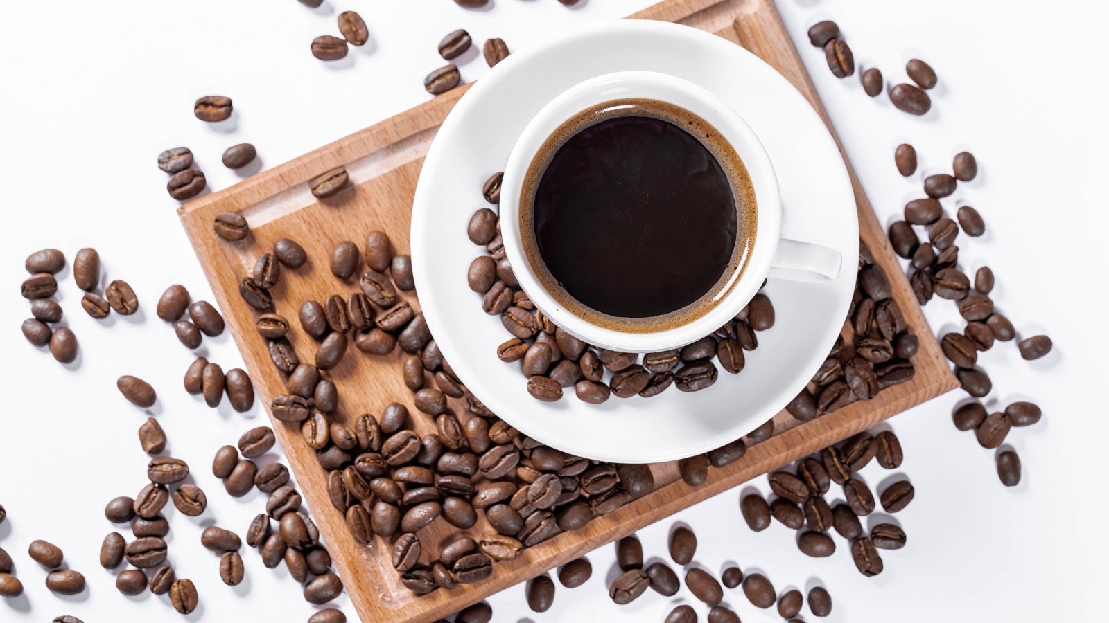 Белая чашка кофе на доске с кофейными зернами