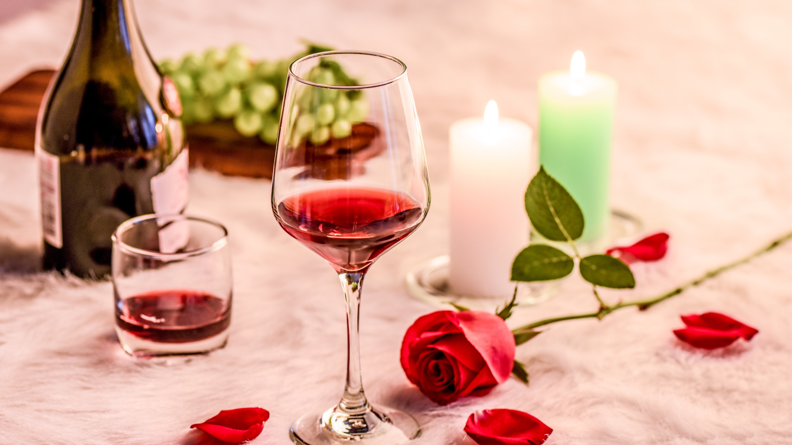 Вино на кровати с розой, виноградом и зажженными свечами