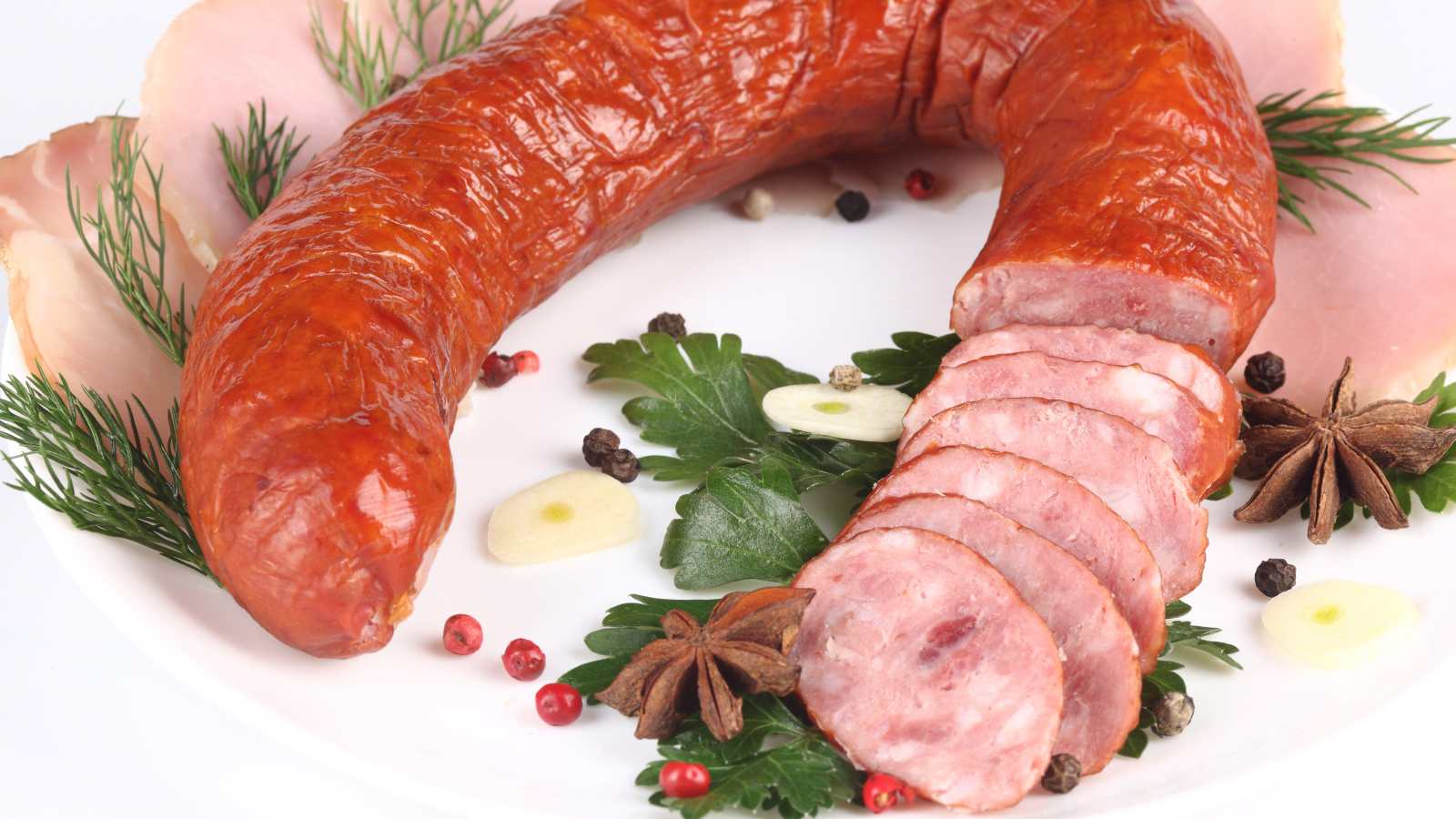 Аппетитная колбаса на белом фоне со специями и зеленью