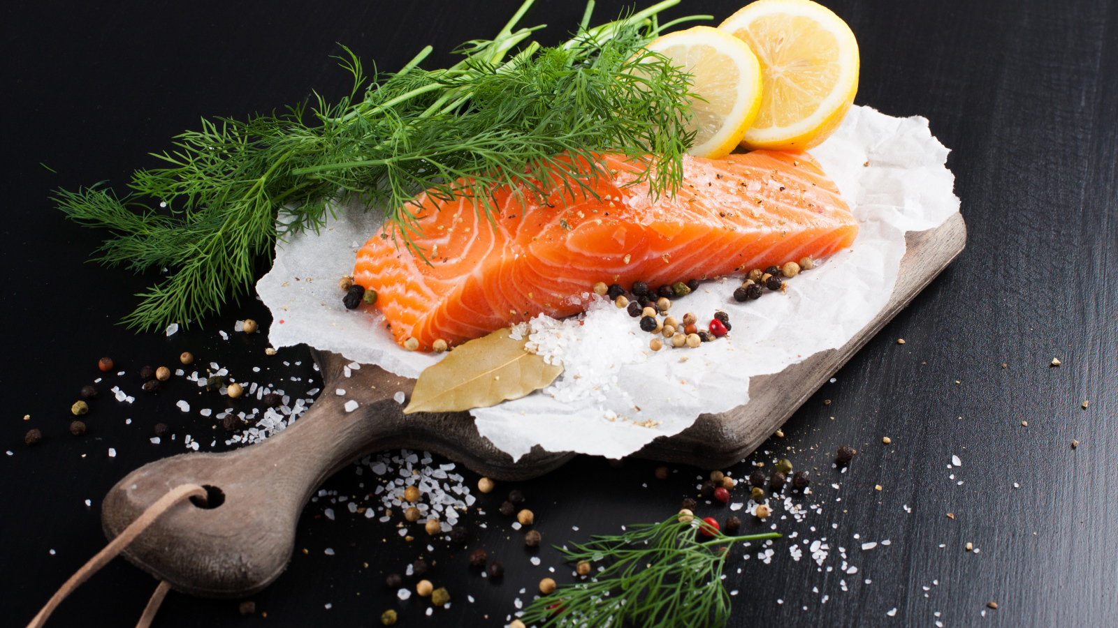 Кусок красной рыбы на доске с укропом и лимоном 