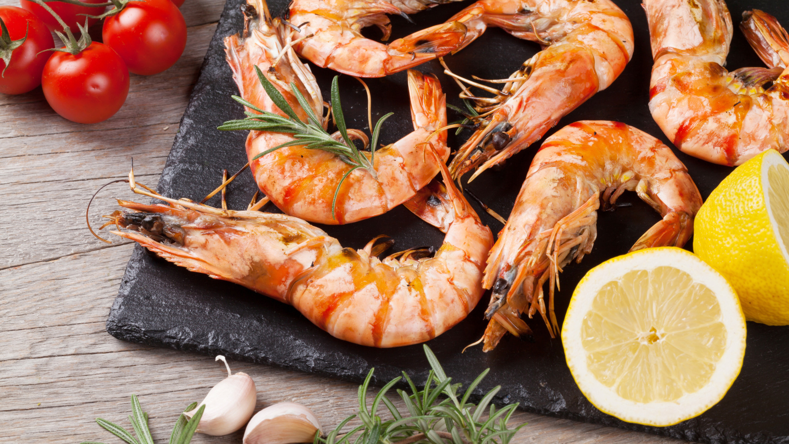 Вареные креветки на столе с лимонами и помидорами