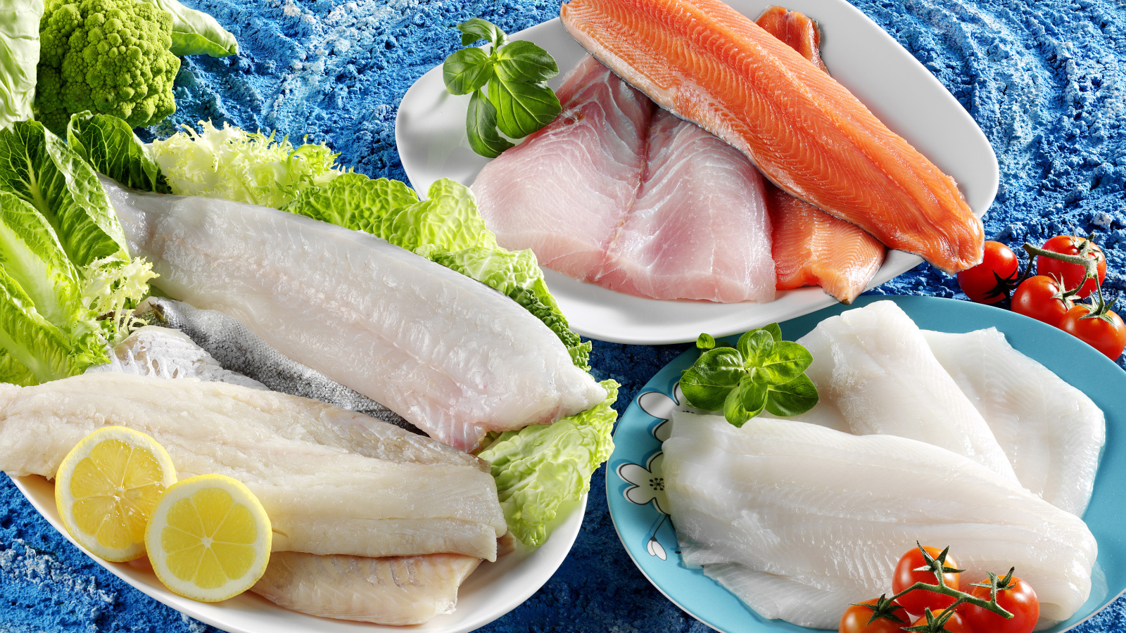 Филе рыбы на тарелках с помидорами и листьями салата