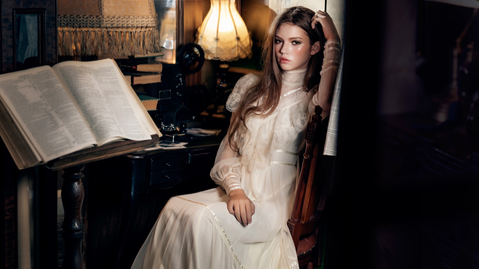 Девушка в красивом белом платье сидит на стуле у стола