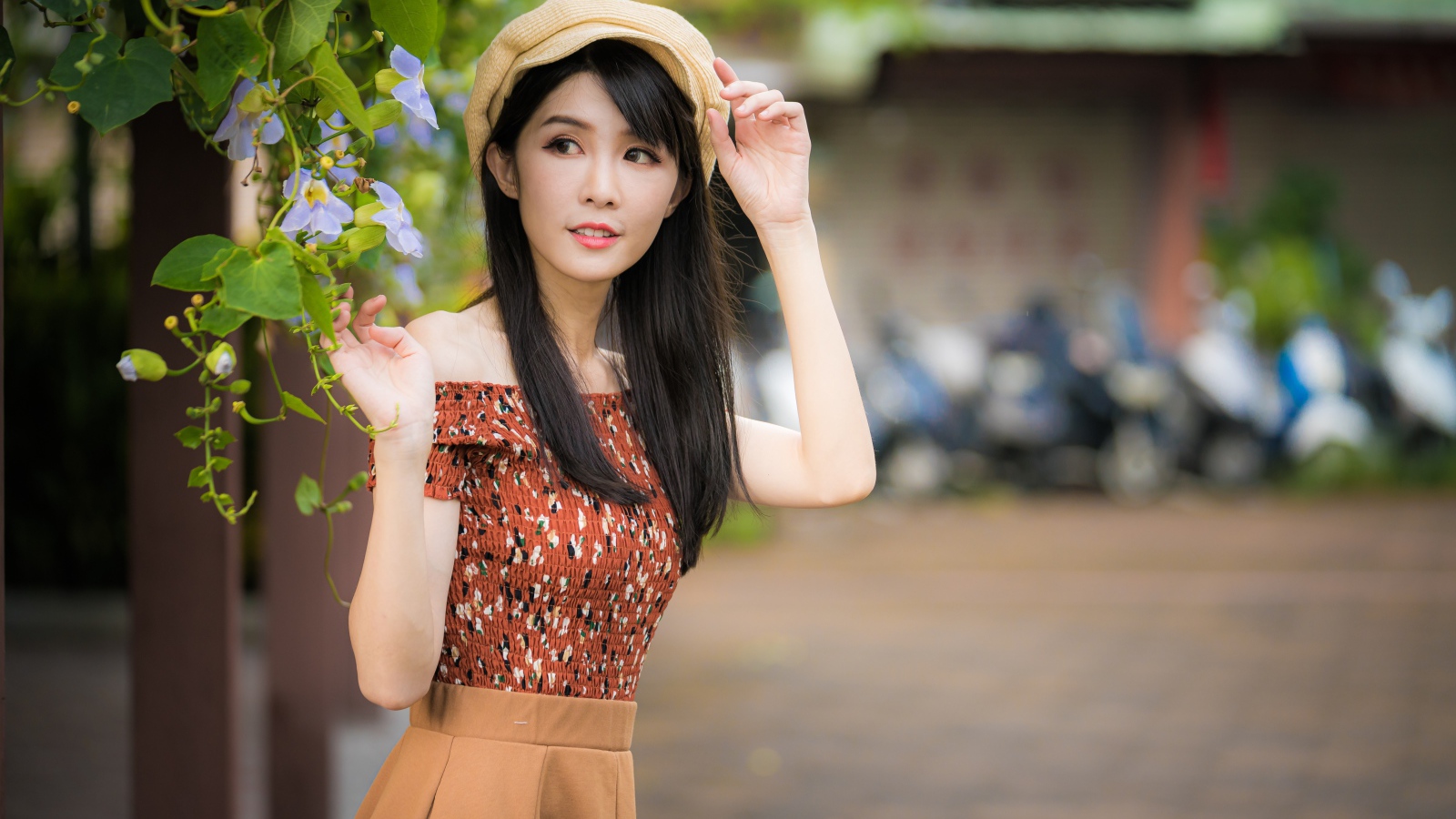 Молодая девушка азиатка в кепке стоит у голубых цветов