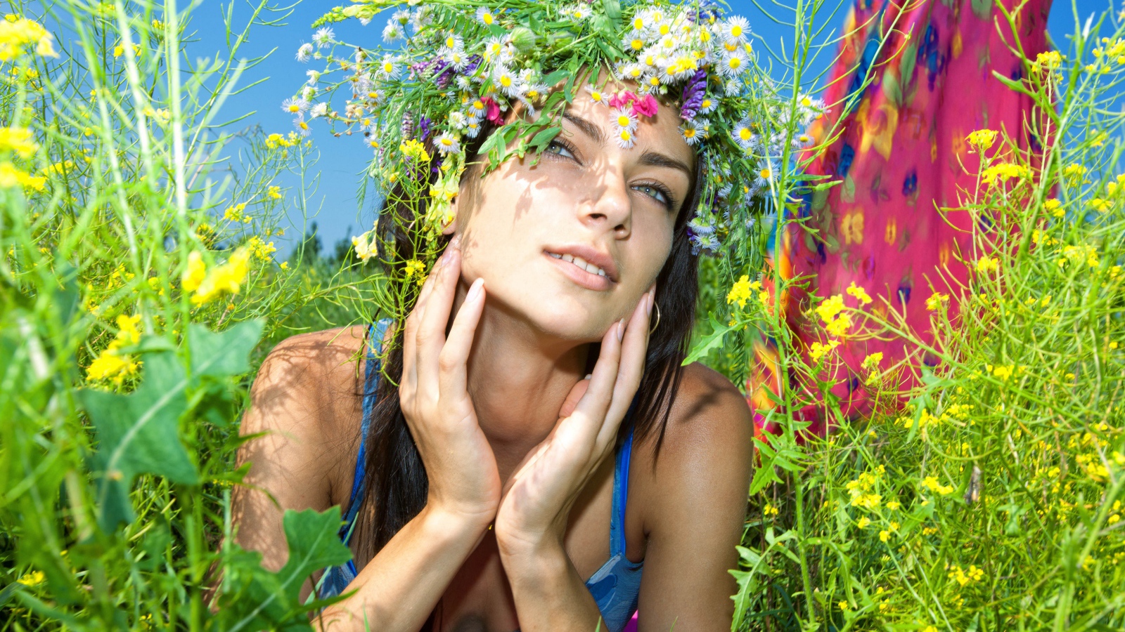 Молодая девушка с венком из полевых цветов лежит в траве