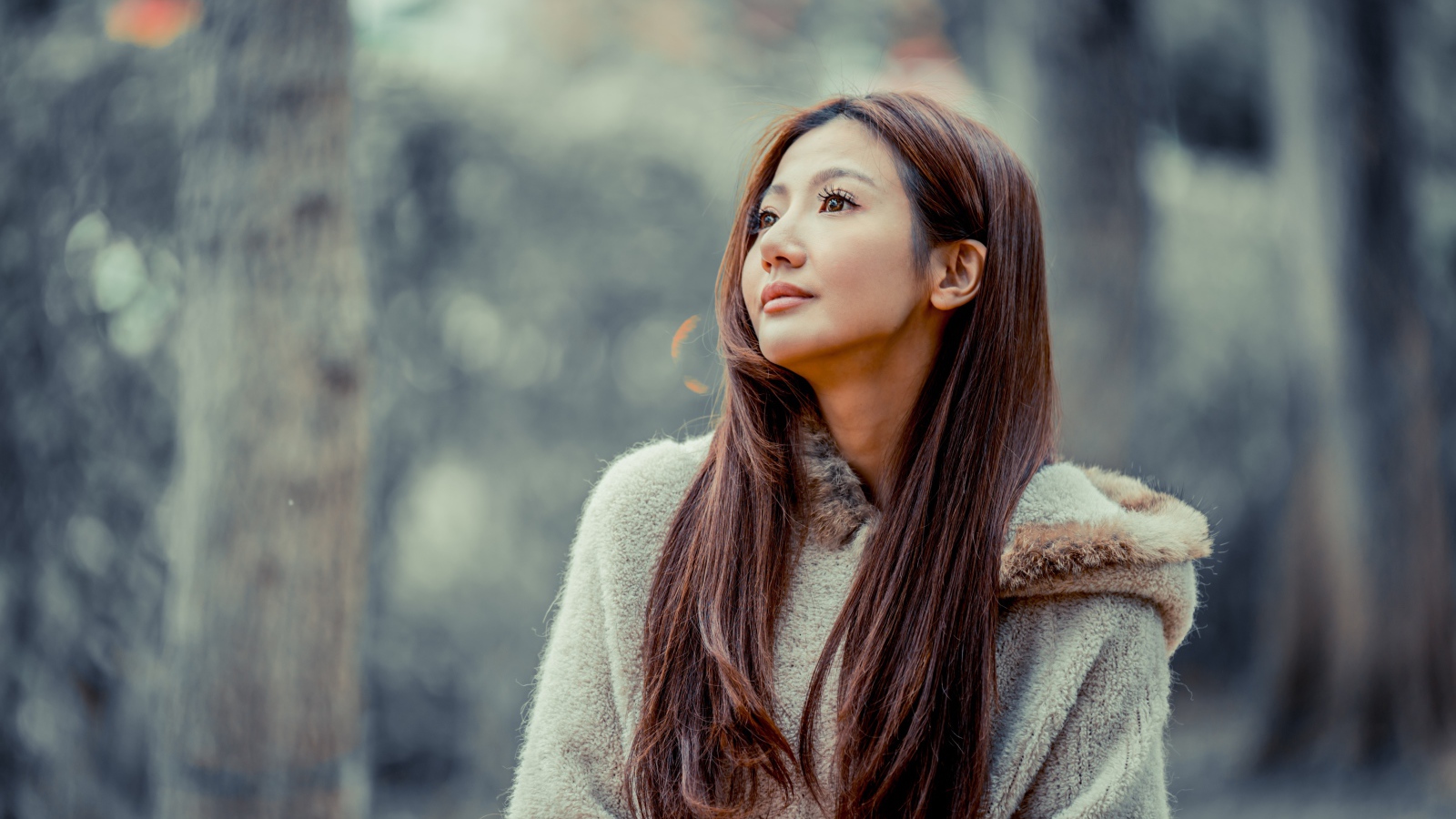 Длинноволосая девушка азиатка смотрит в сторону