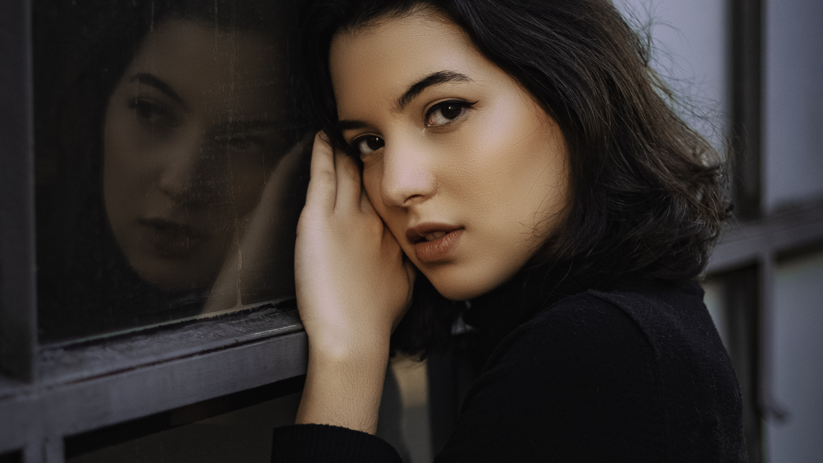 Красивая кареглазая девушка стоит у окна