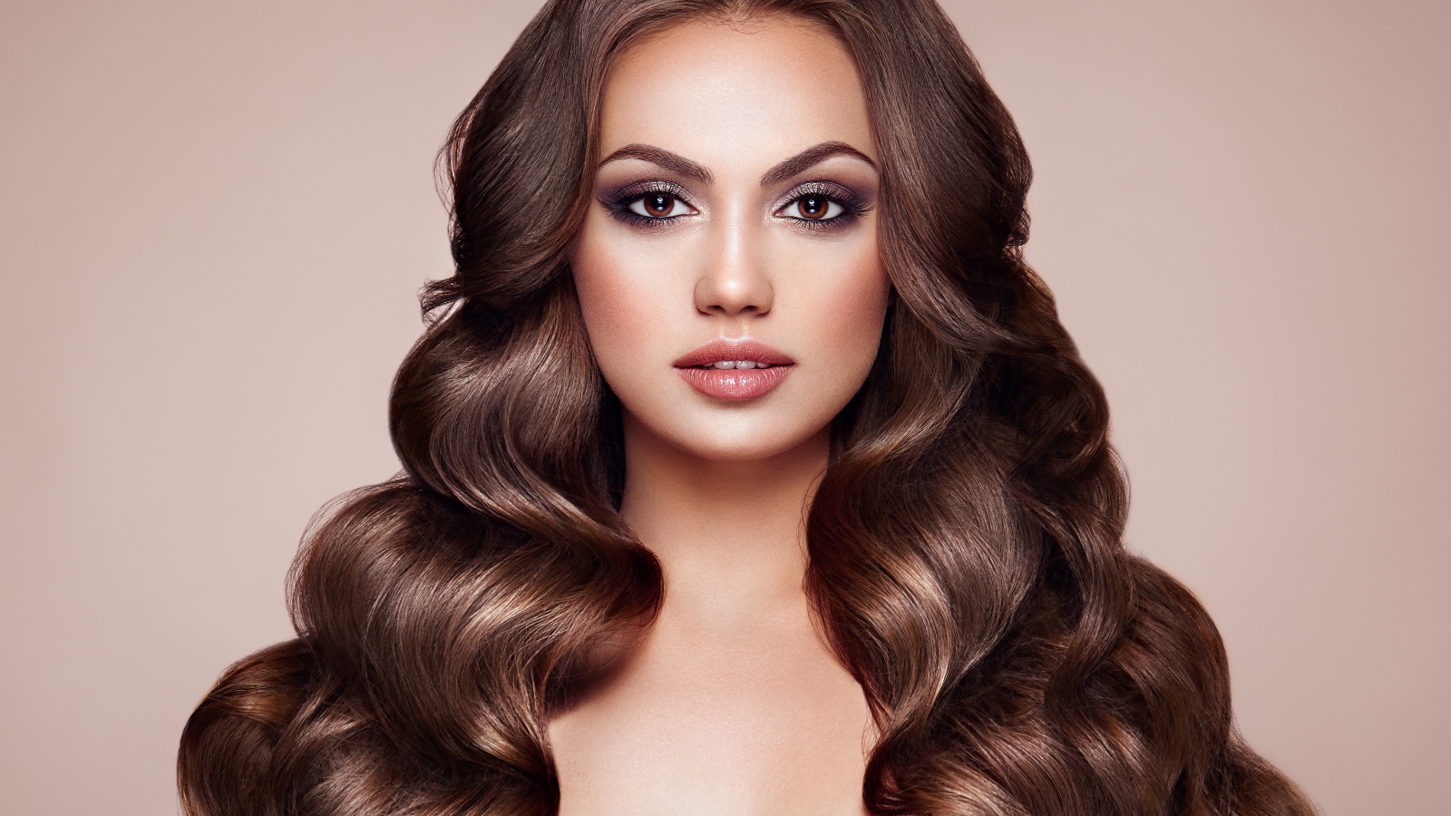 Красивая кареглазая девушка с длинными волосами на бежевом фоне