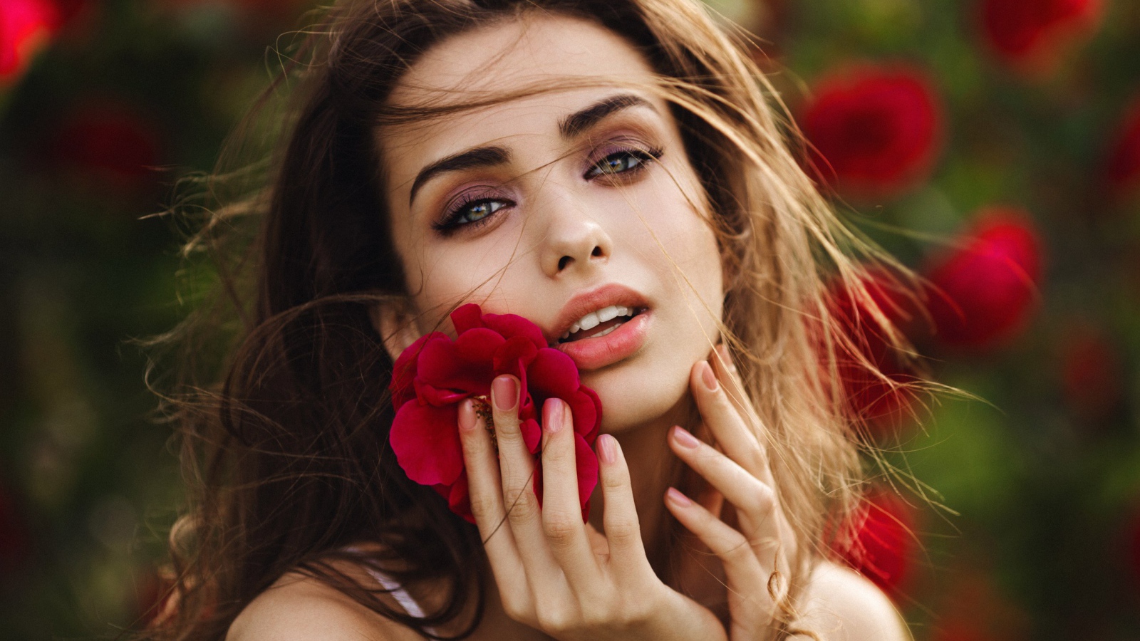 Красивая девушка шатенка с цветком у лица