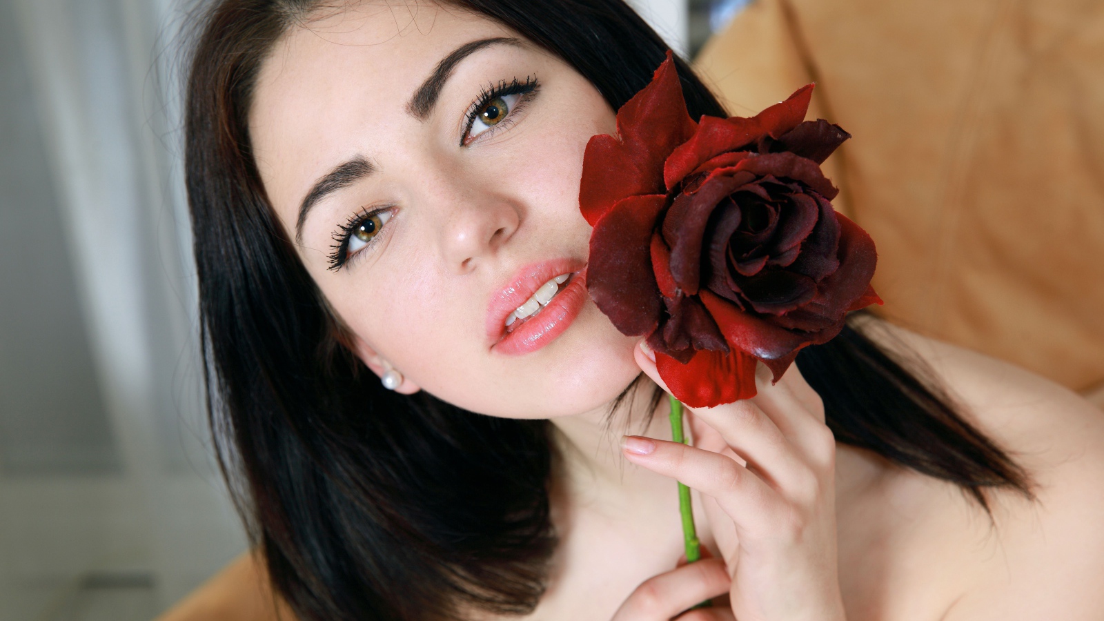 Красивая брюнетка с розой в руке крупным планом