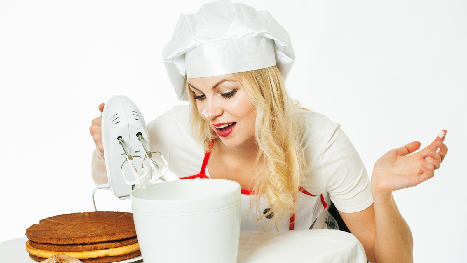 Красивая девушка повар взбивает крем для торта миксером