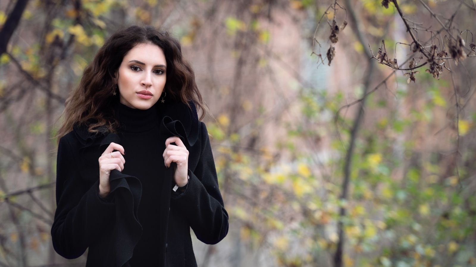 Красивая девушка в черном пальто осенью