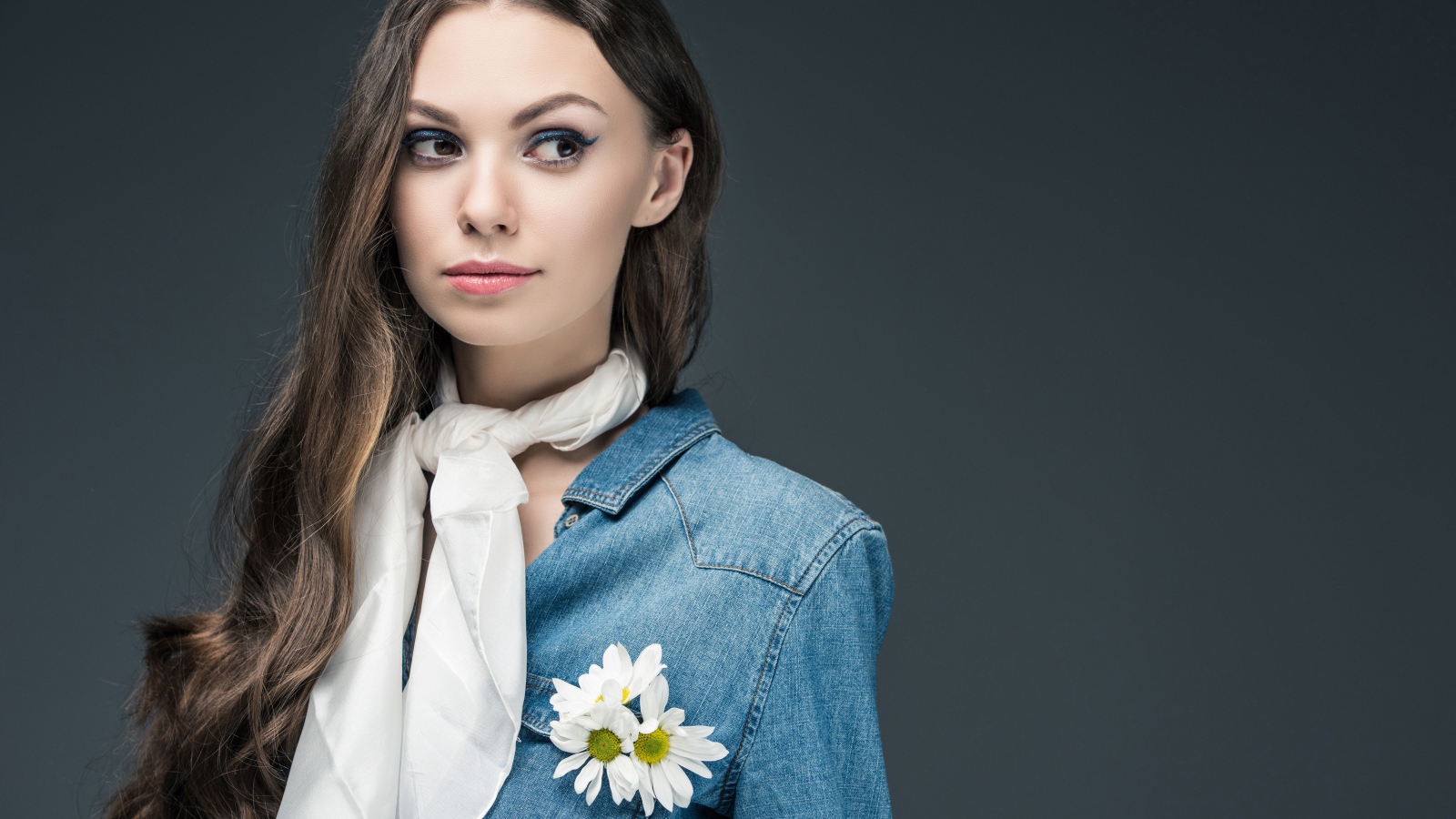 Красивая девушка в джинсовой куртке с шарфом на шее 