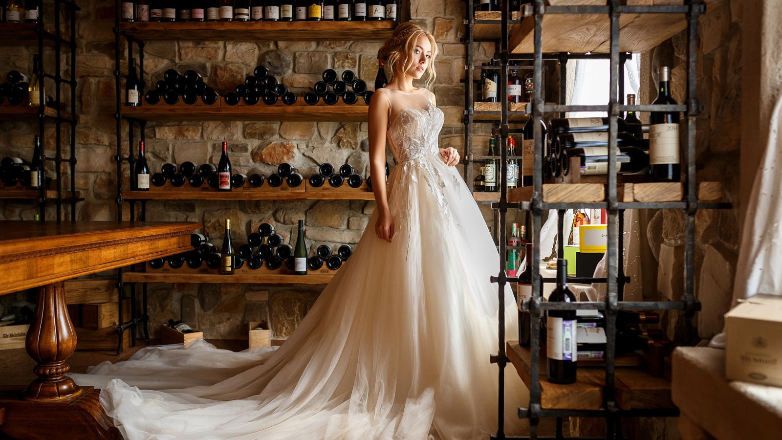 Красивая девушка в пышном свадебном платье в винном погребе