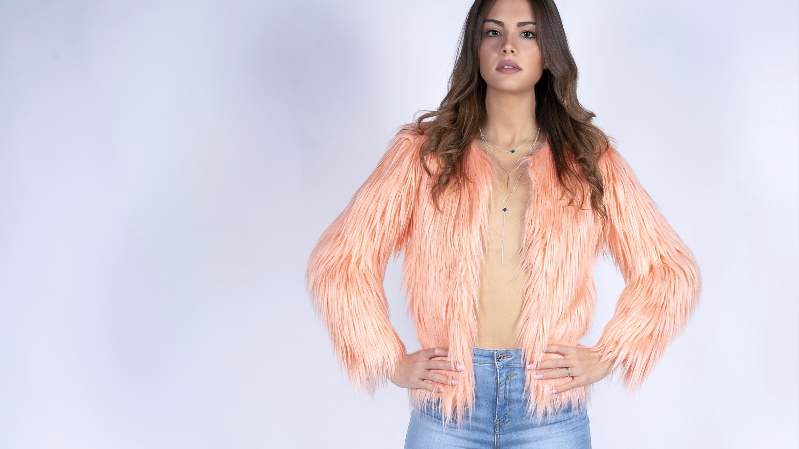 Красивая девушка в розовой шубе и джинсовых шортах