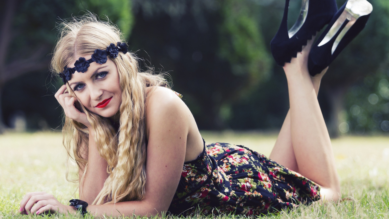 Красивая девушка в черных туфлях лежит на зеленой траве