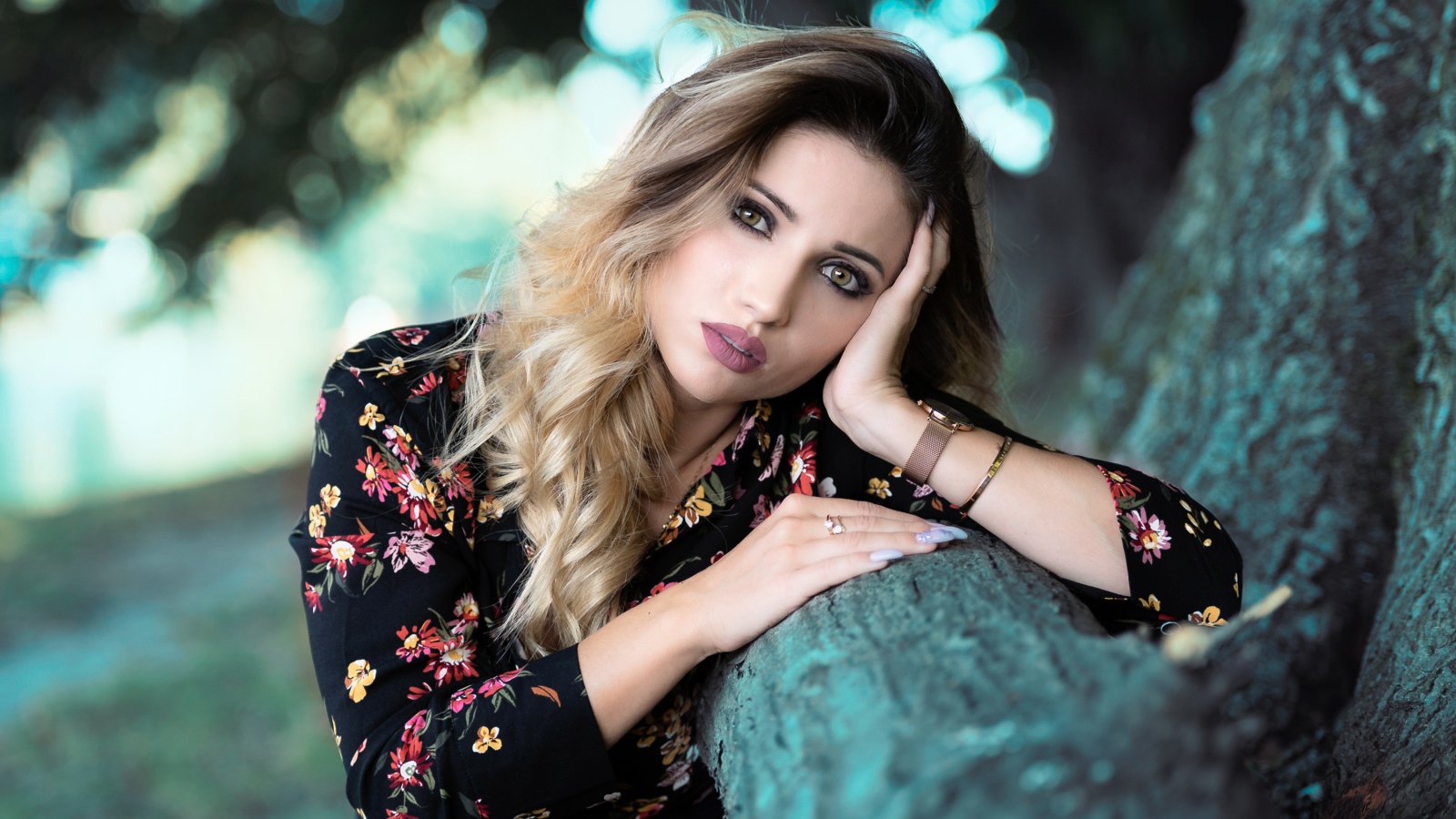 Красивая девушка в цветастом платье у дерева