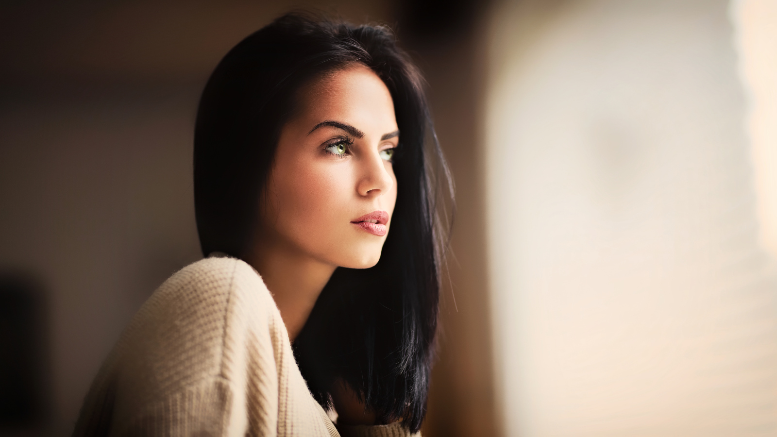 Красивая девушка зеленоглазая смотрит в окно 