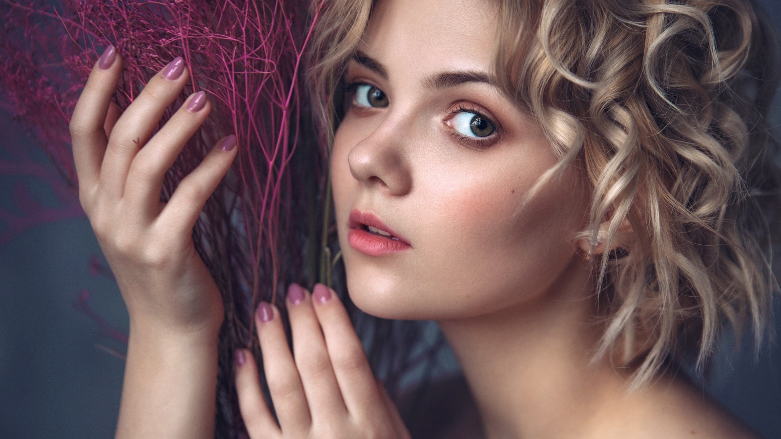 Красивая молодая блондинка с красным растением в руках