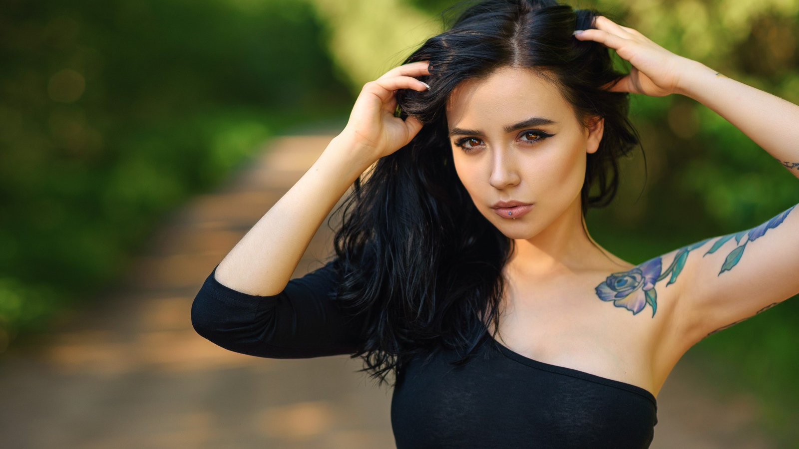 Красивая молодая девушка в черном с татуировкой на руке