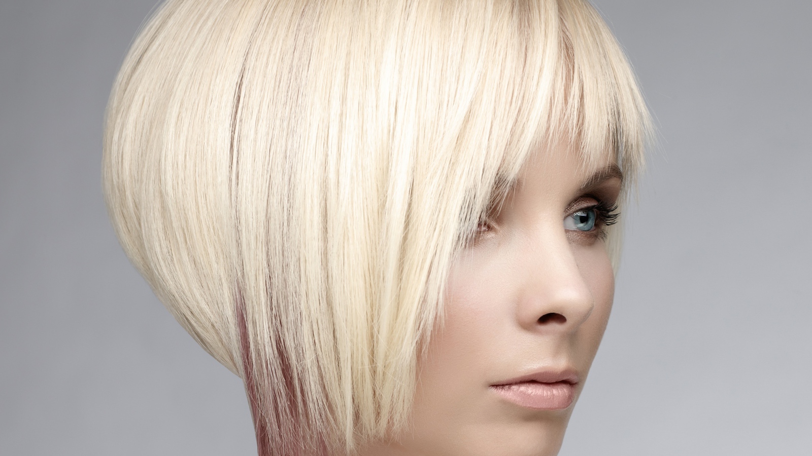 Голубоглазая девушка блондинка с короткой стрижкой на сером фоне