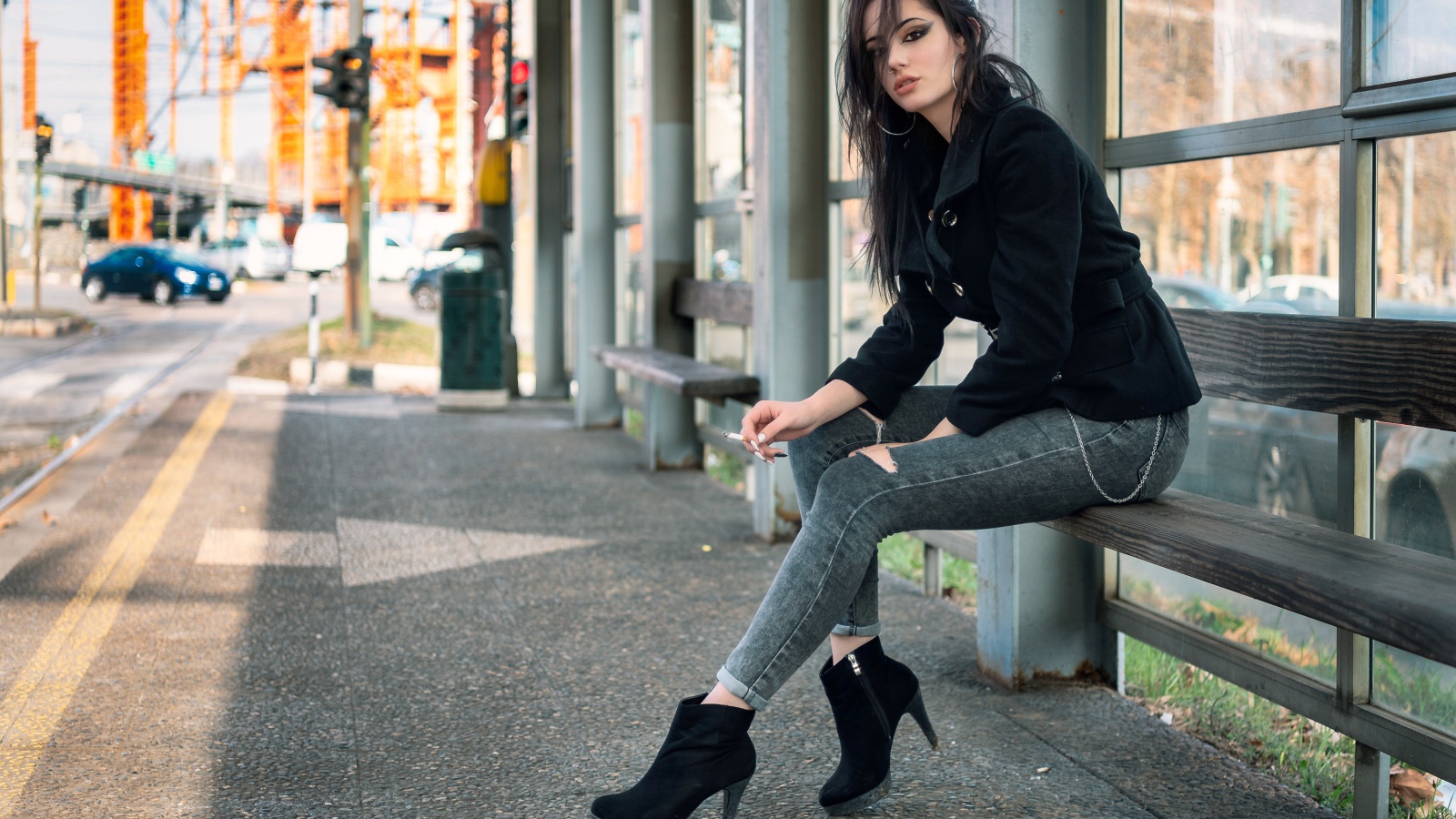 Девушка неформалка сидит на автобусной остановке