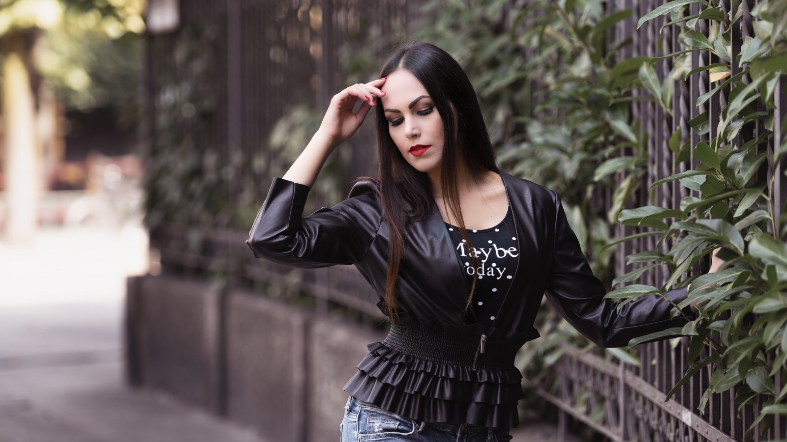 Длинноволосая брюнетка в черной куртке у забора