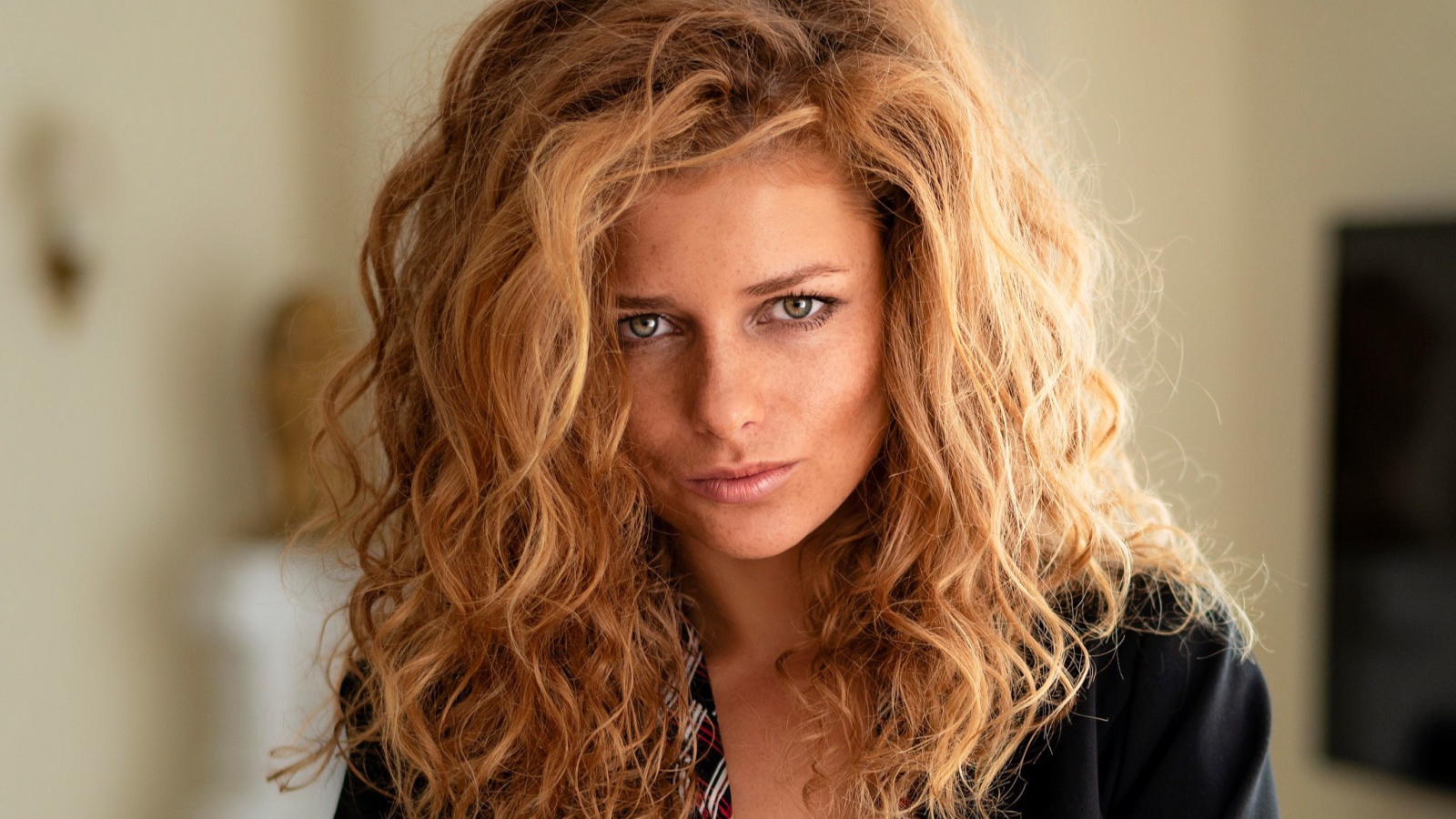 Рыжеволосая женщина с зелеными глазами в черном пиджаке