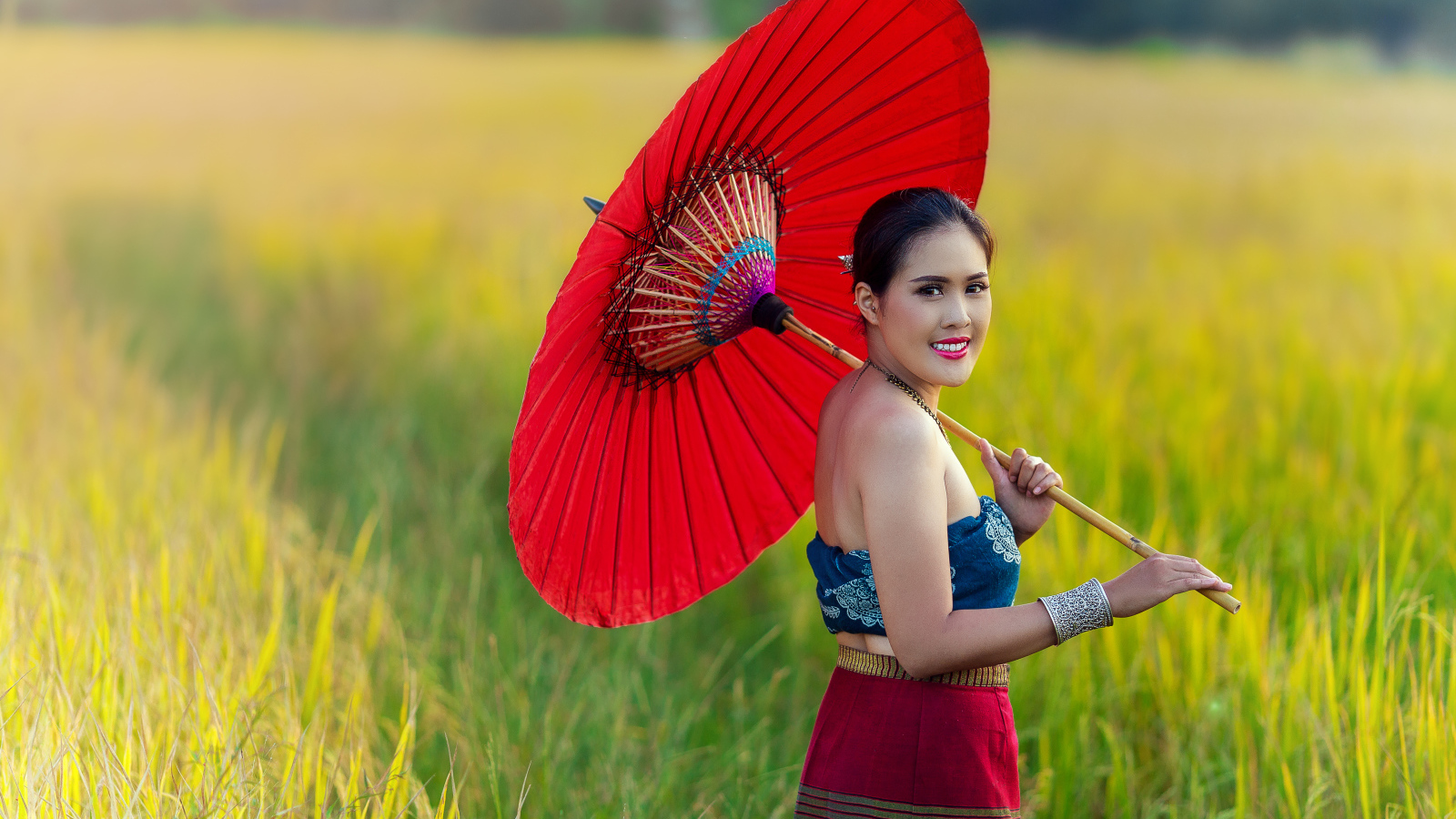 Улыбающаяся девушка азиатка с красным зонтом