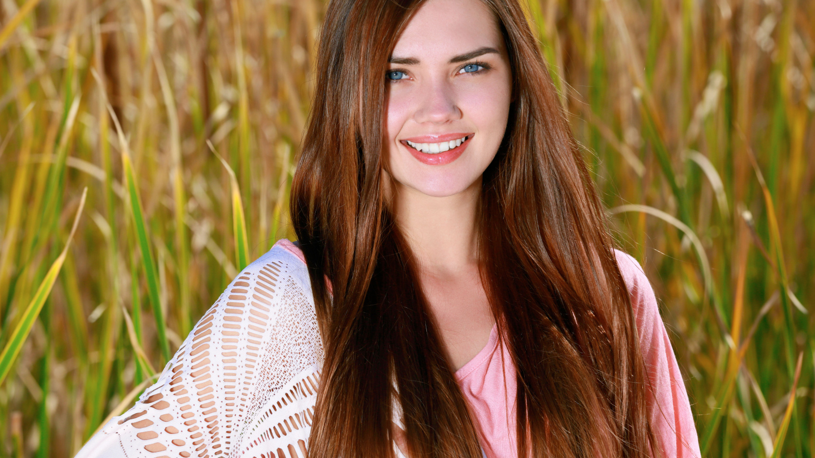 Улыбающаяся голубоглазая шатенка на поле