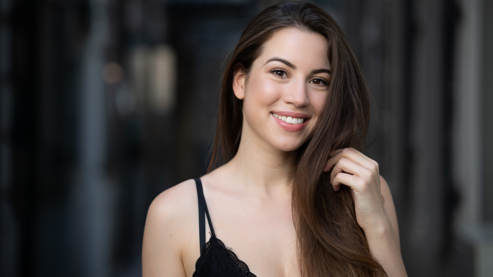 Улыбающаяся девушка держит длинные волосы