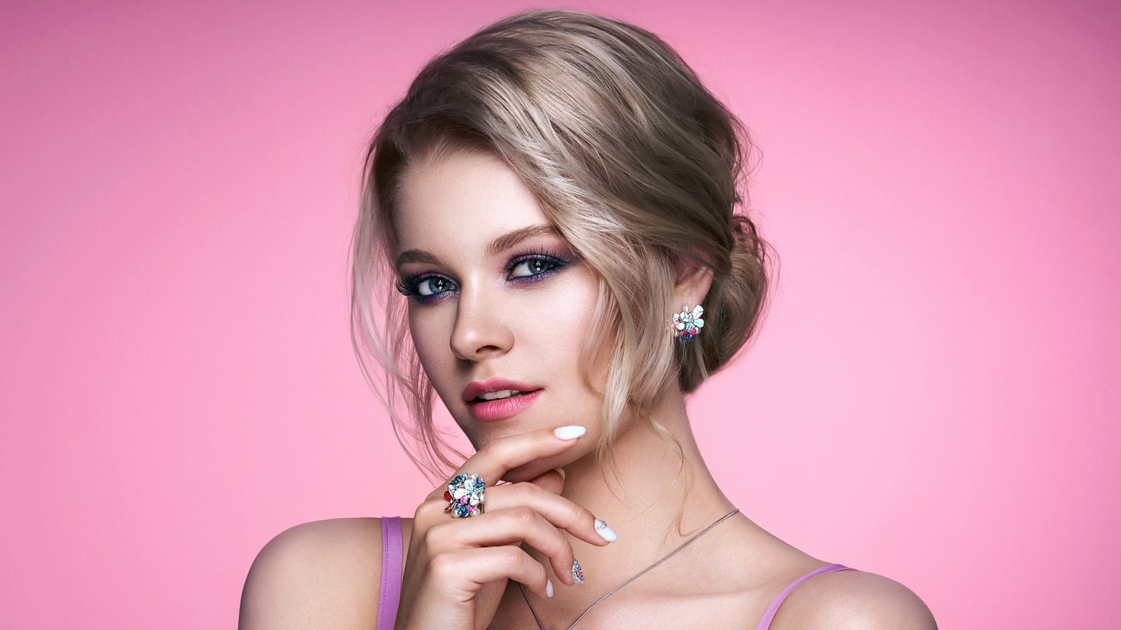 Стильная блондинка с прической на розовом фоне