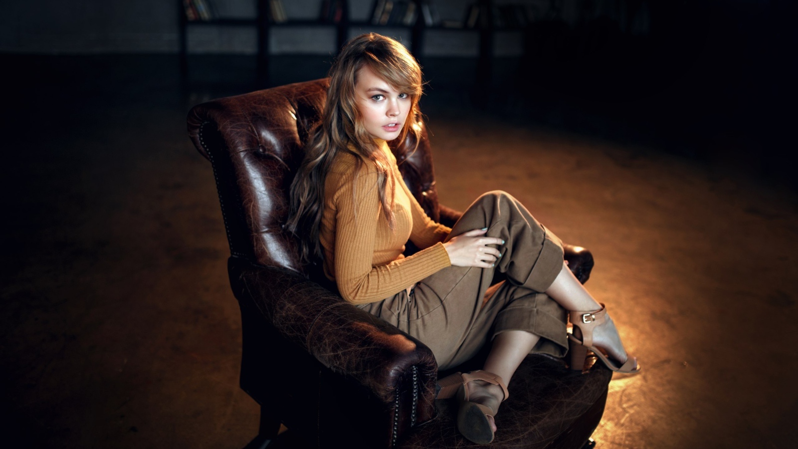 Нежная девушка модель сидит в кожаном кресле