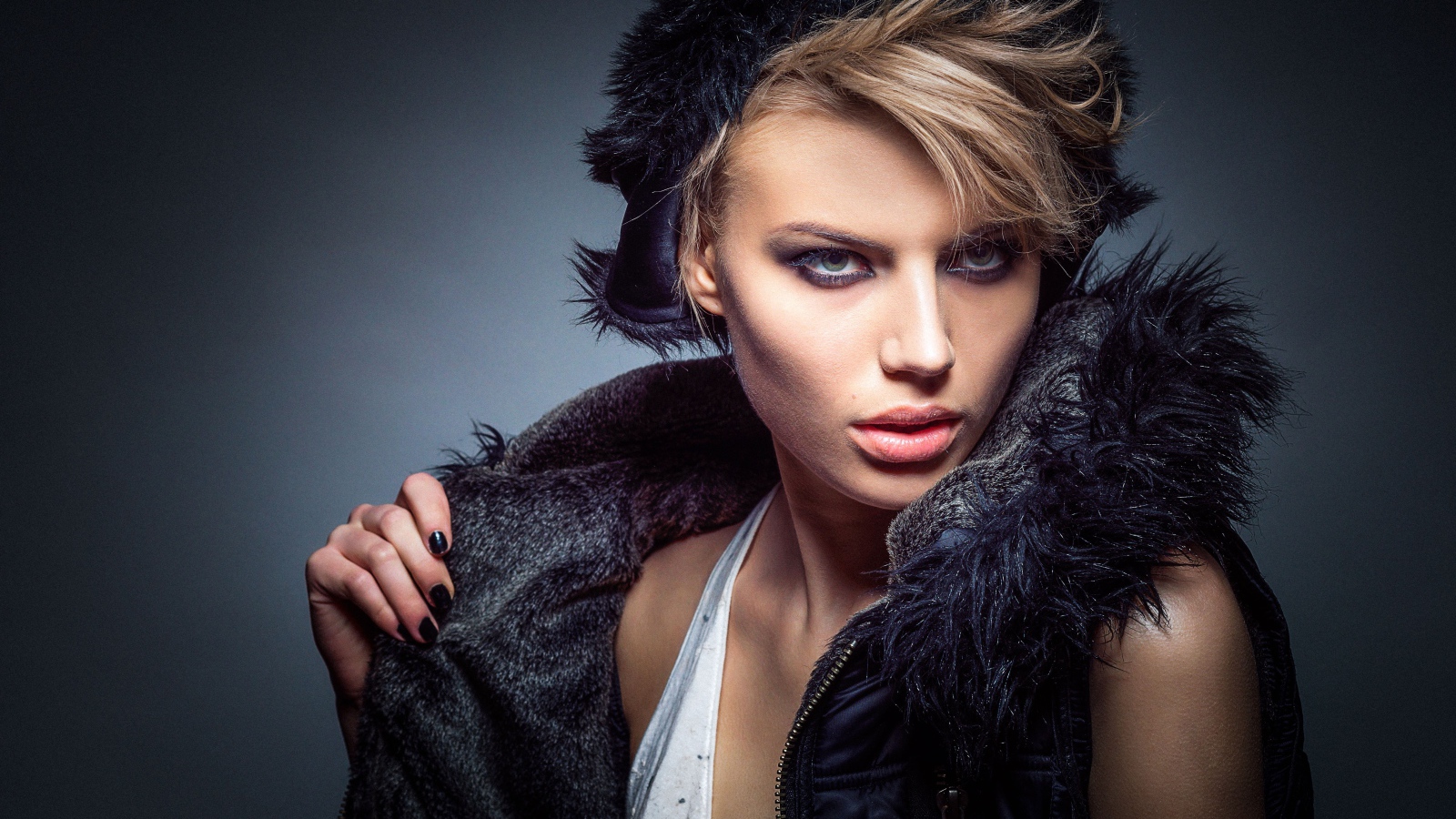 Девушка в теплой жилетке и шапке на сером фоне