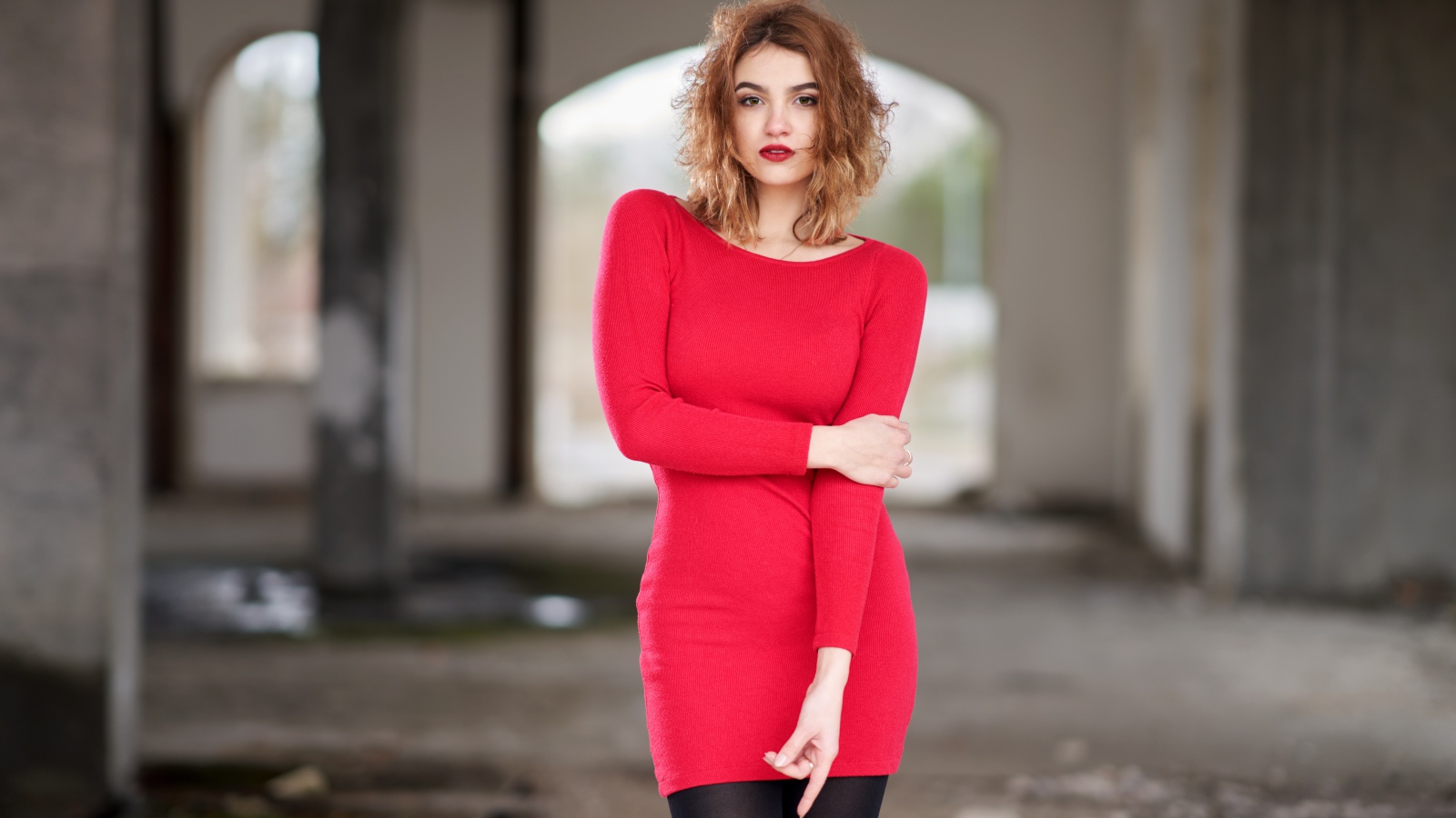 Молодая девушка в красном платье в старом здании
