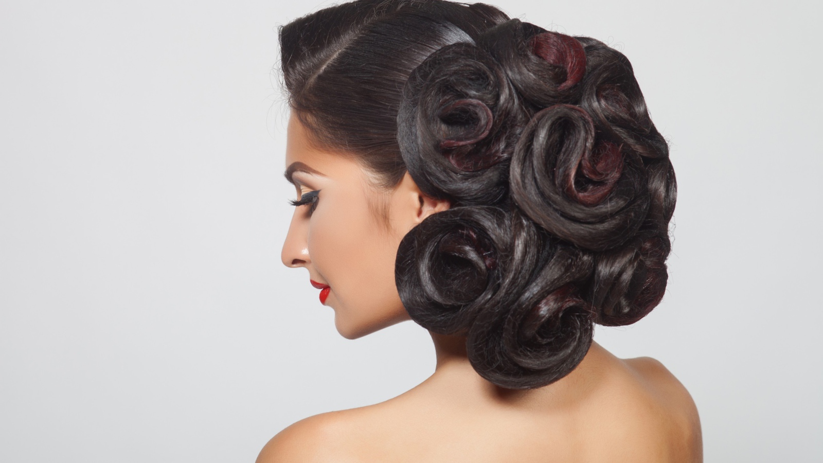 Молодая девушка с красивой прической на сером фоне