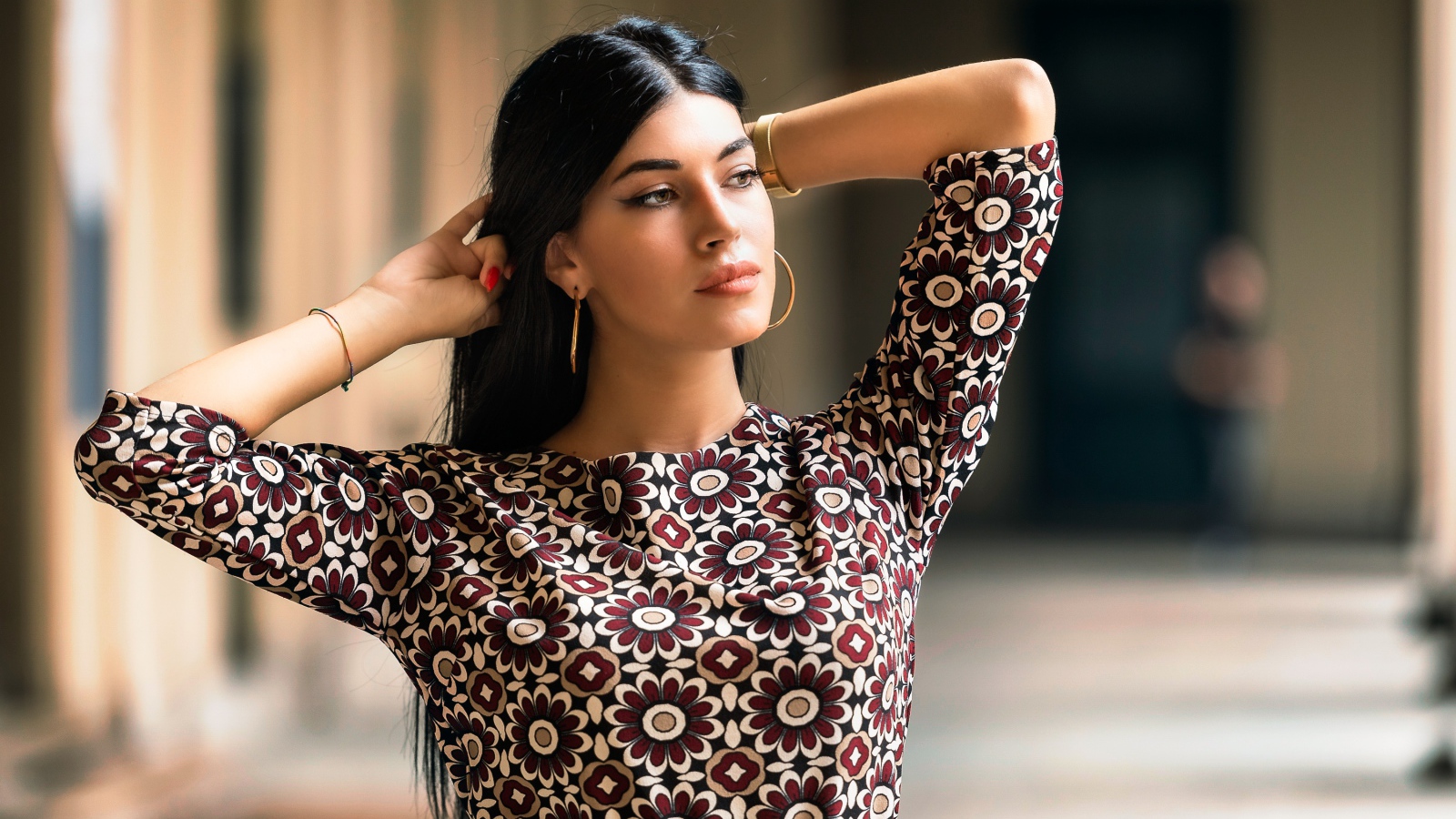 Молодая длинноволосая шатенка с руками в волосах