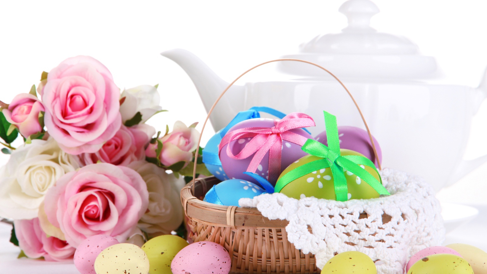 Корзина с пасхальными яйцами на столе с букетом роз и белым чайником
