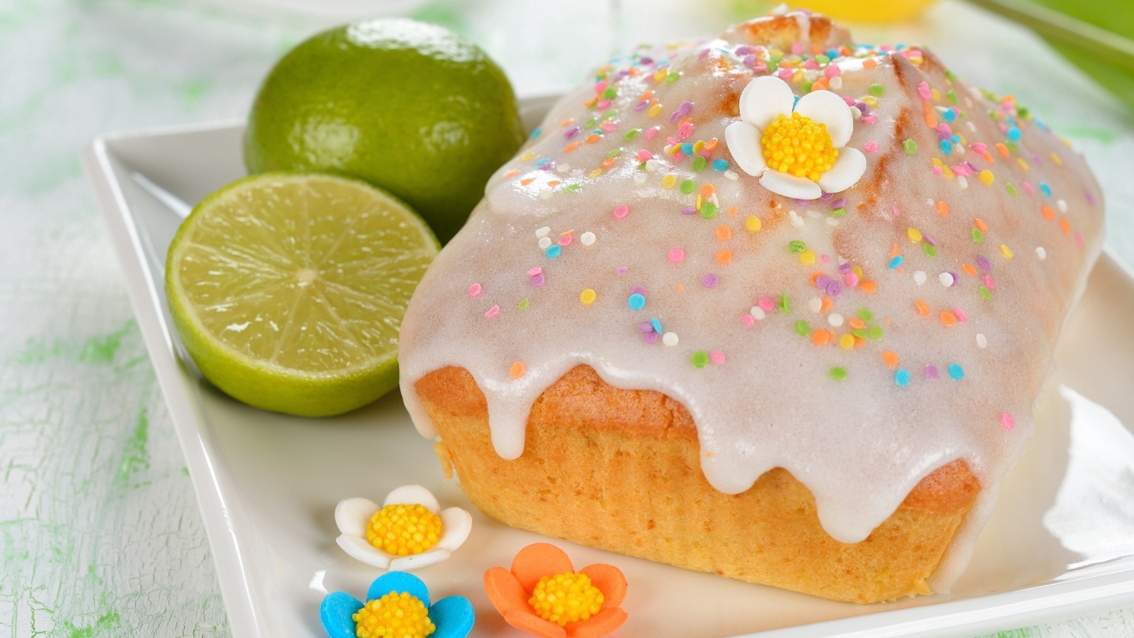 Красивый пасхальный кулич на белой тарелке с лаймом и сахарными цветами