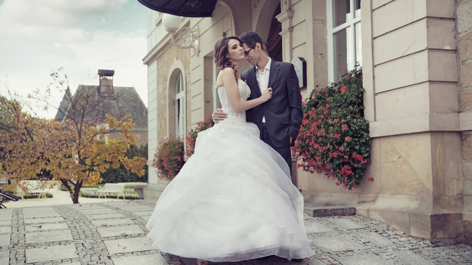 Жених и невеста стоят у здания 