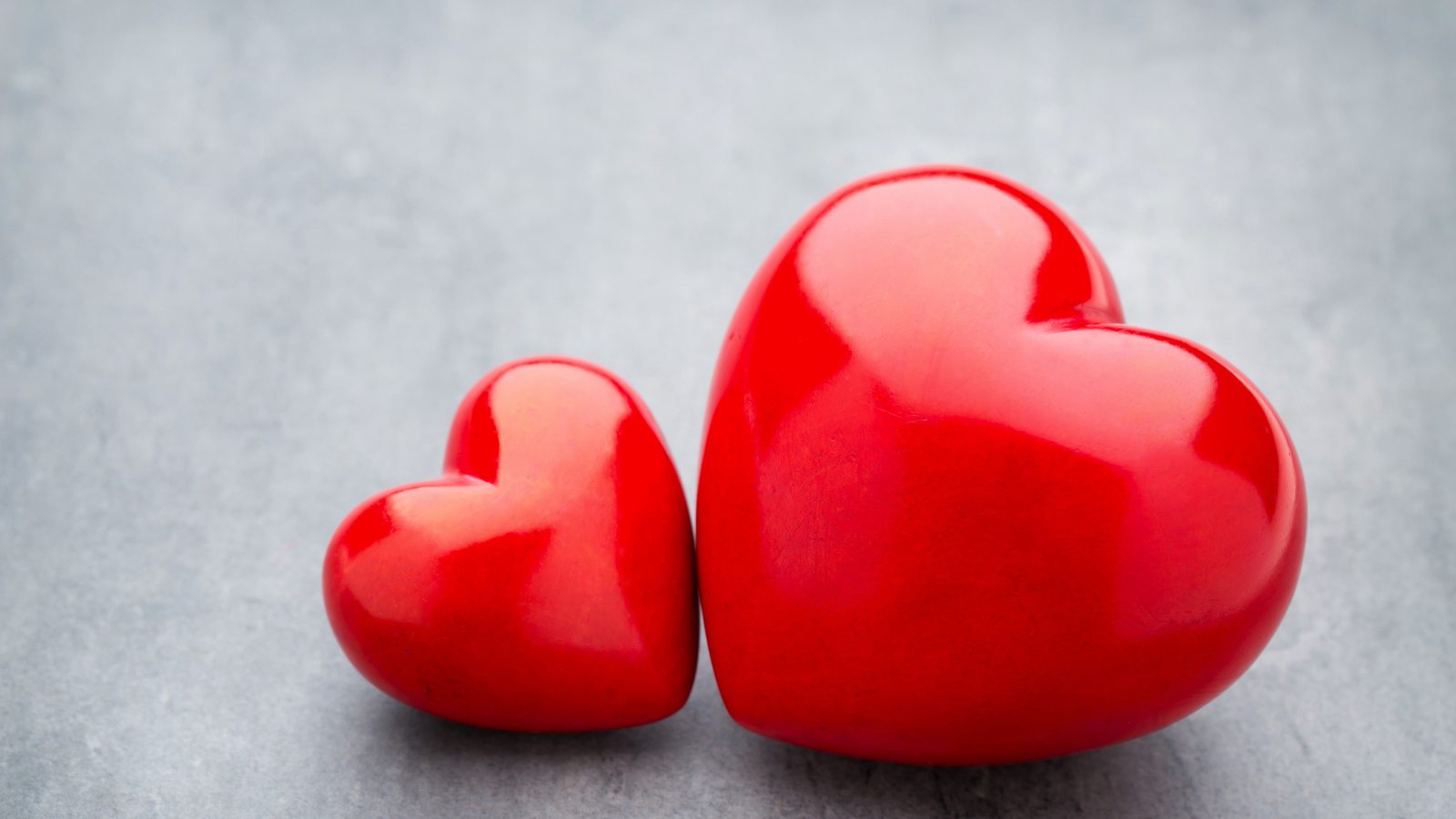Большое и маленькое красное сердце на сером столе