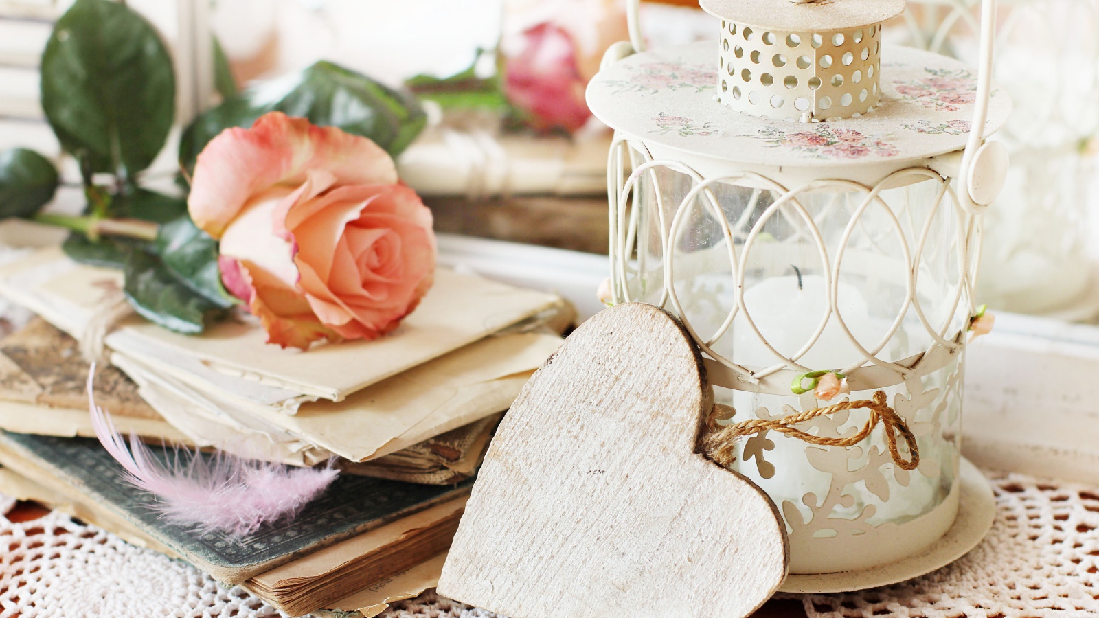 Фонарь со свечей на столе с розой, сердцем и книгами