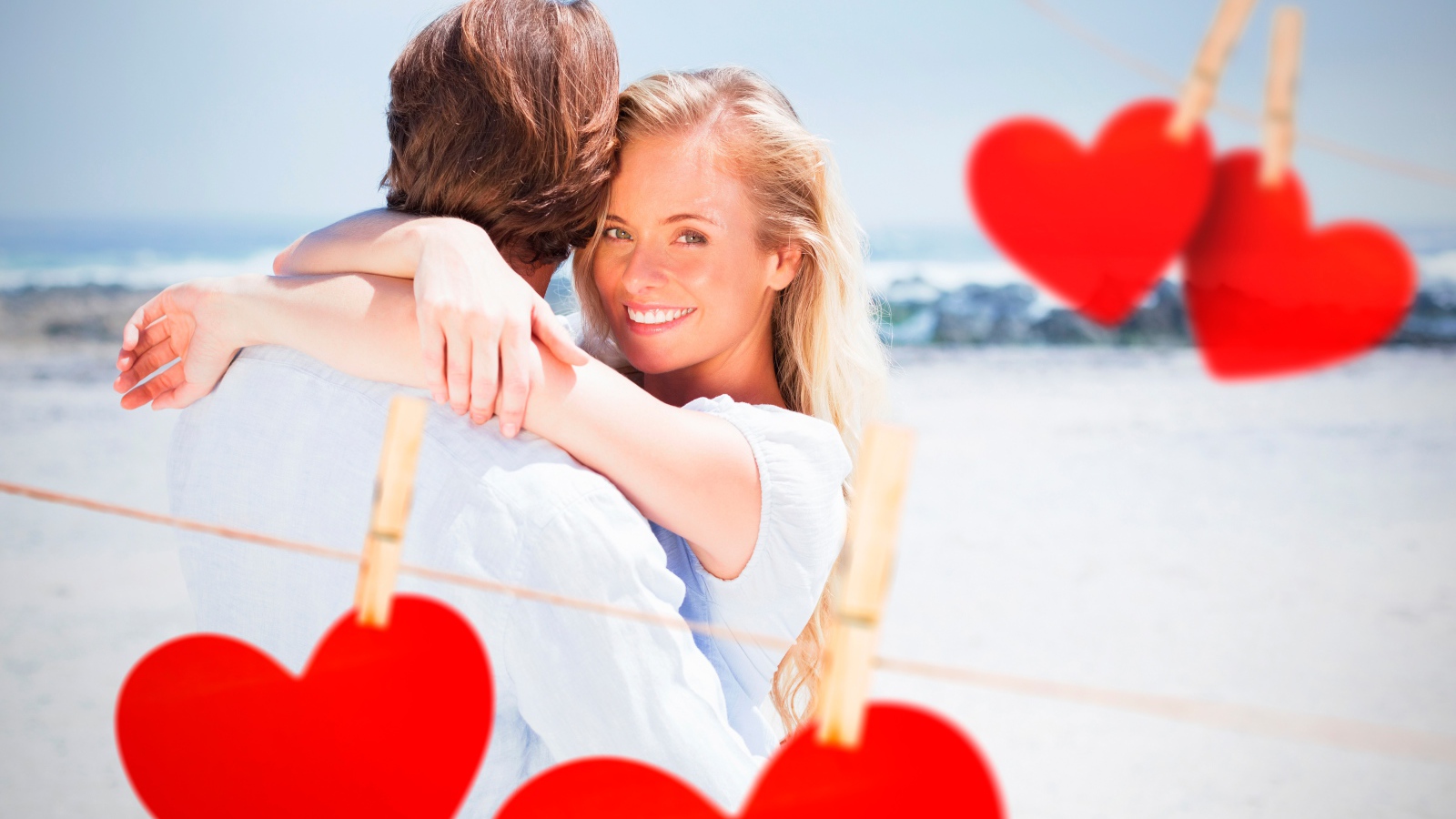 Влюбленная пара на берегу моря с красными сердечками
