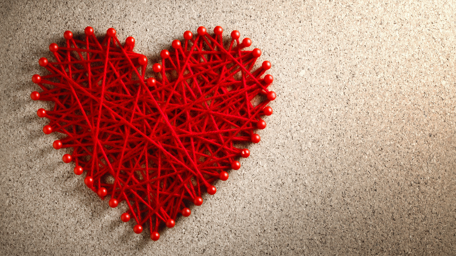 Сердце из красных нитей и невидимок на сером фоне