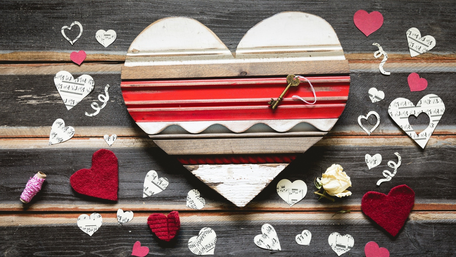 Деревянное сердце с бумажными сердечками на столе