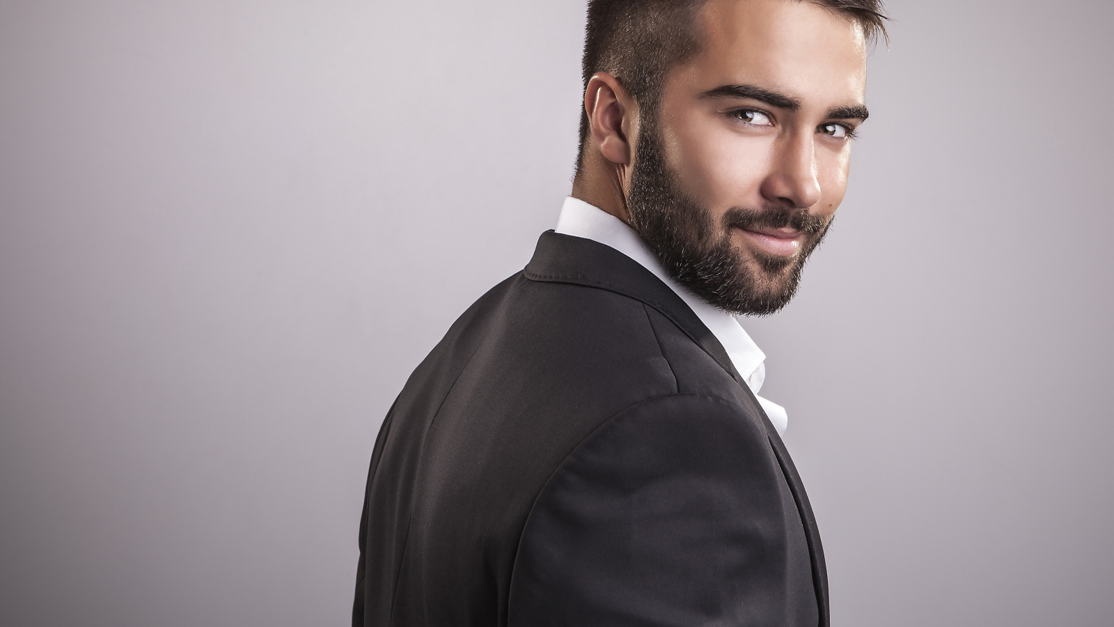 Красивый мужчина модель с бородой на сером фоне